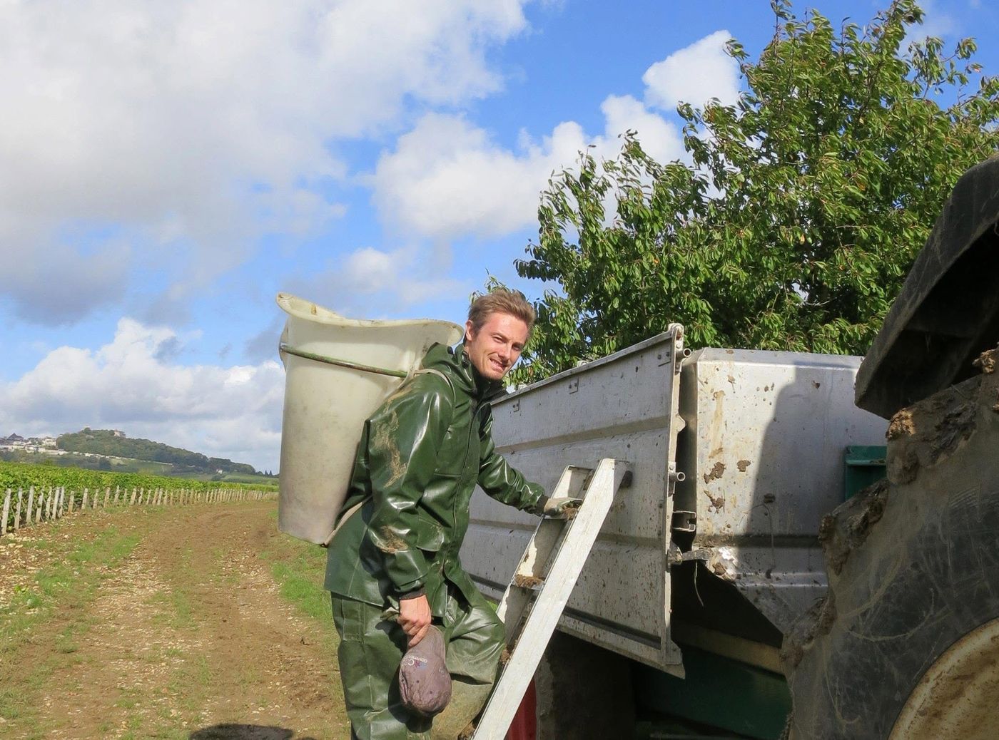 A picker carrying a hotte on his back, climbing to the trailer